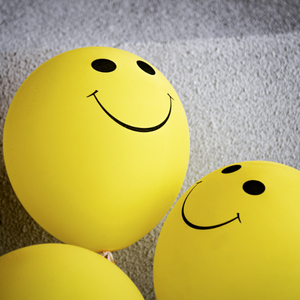 Three yellow ping pong balls with smiley faces like happy emoji's