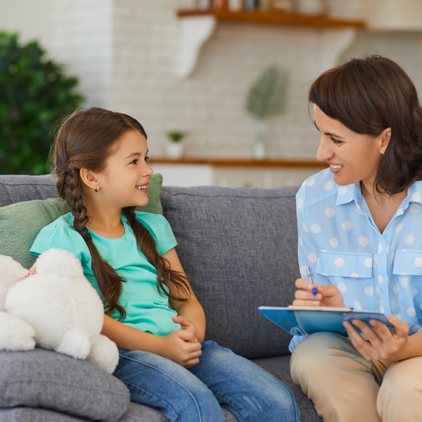 Child sitting comfortably with a therapist in a calm, welcoming clinic space, talking together in a supportive and reassuring environment
